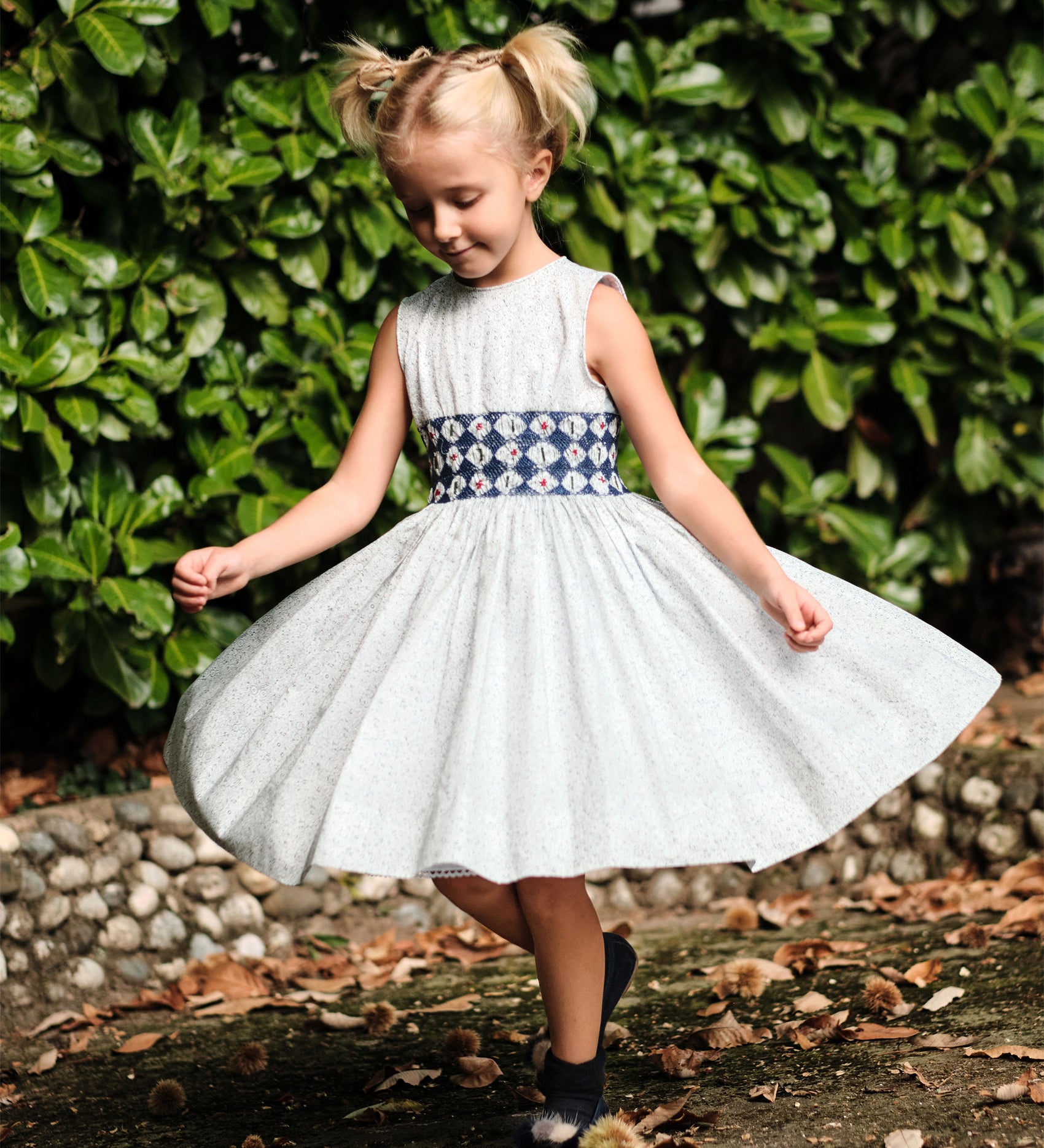 Girl wearing the Cashmirino Evelyn hand-smocked Liberty Green Flowers cotton dress with cobalt blue embroidery and teal chambray back.