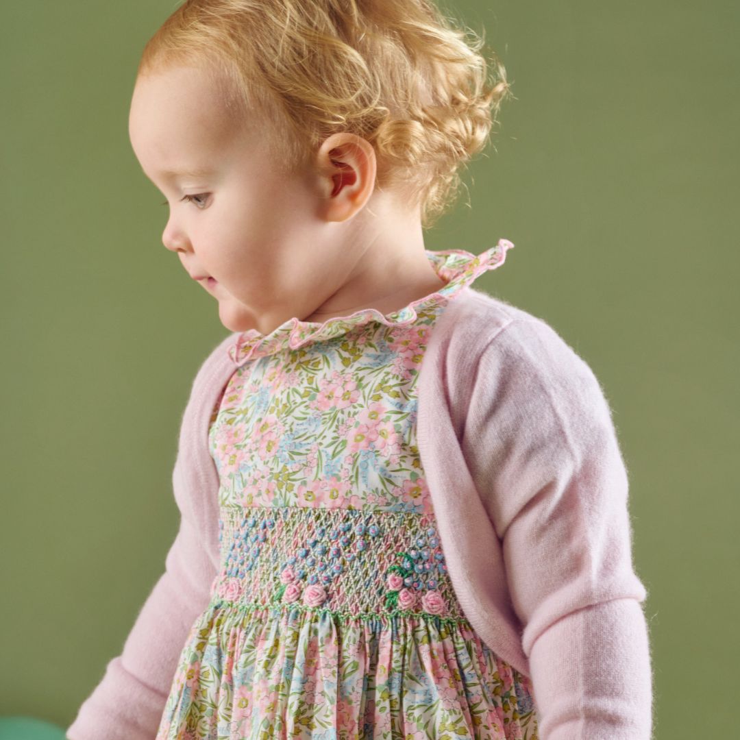 Baby girl wearing Cashmirino pearl pink cashmere shrug