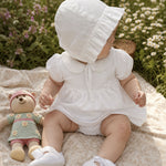 Baby girl in a white Peruvian Pima cotton dress set with crochet Peter Pan collar on a picnic blanket.