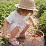 Baby girl wearing Peruvian Pima cotton bodysuit and shorts set with hand-embroidered roses picking strawberries.