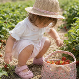 Baby girl wearing Peruvian Pima cotton bodysuit and shorts set with hand-embroidered roses picking strawberries.